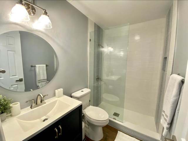 bathroom featuring a shower with shower door, vanity, and toilet