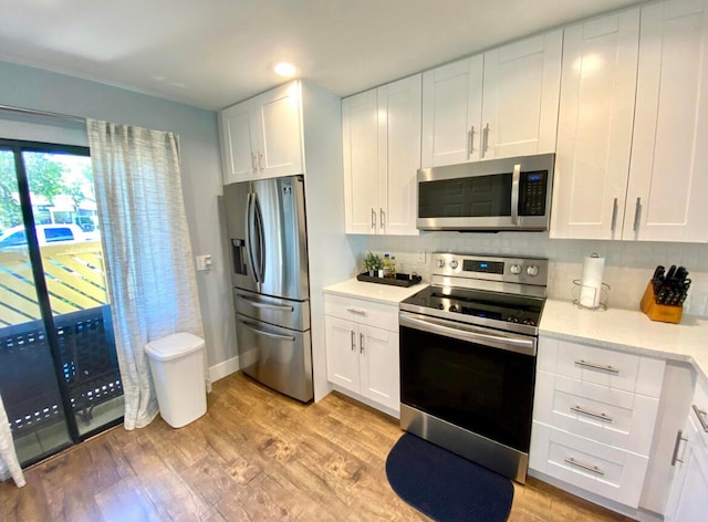 kitchen featuring backsplash, white cabinets, light wood-type flooring, and stainless steel appliances