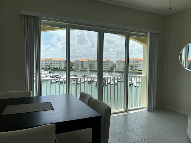 unfurnished dining area featuring light tile patterned floors, a water view, baseboards, and a city view