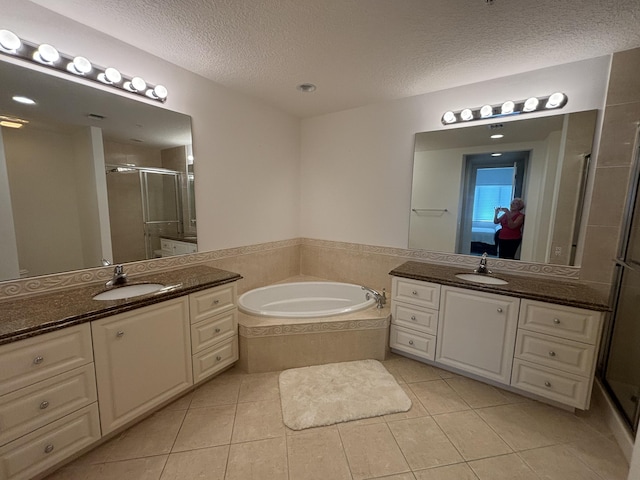 ensuite bathroom with a stall shower, a textured ceiling, a sink, and ensuite bathroom