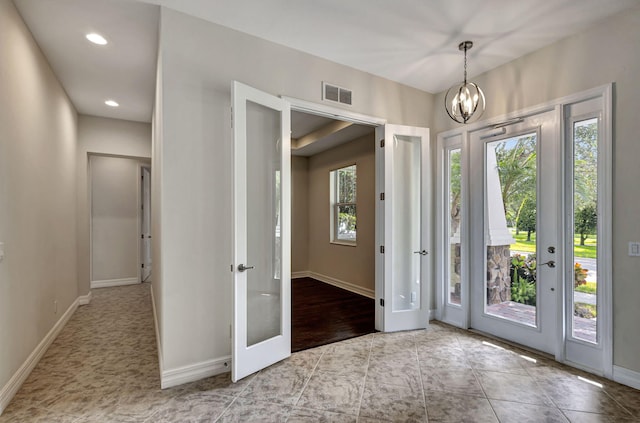 tiled foyer featuring french doors and an inviting chandelier