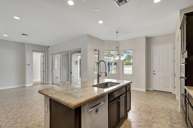 kitchen featuring dark brown cabinetry, sink, light stone counters, an island with sink, and stainless steel appliances