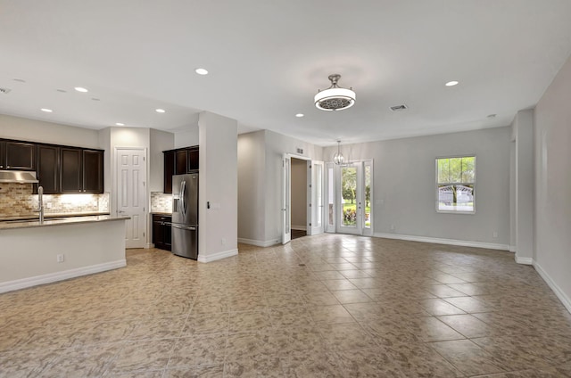 unfurnished living room with baseboards, visible vents, and a sink