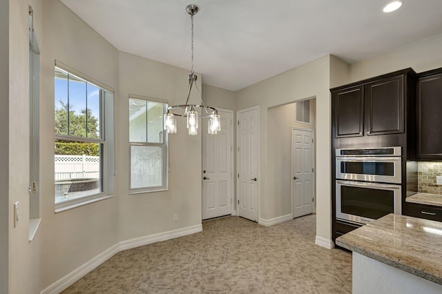 kitchen with baseboards, visible vents, light stone countertops, dark brown cabinets, and double oven