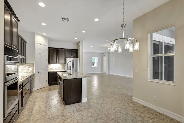 2710 W Mallory Blvd, Jupiter, FL 33458 - kitchen with a chandelier, decorative backsplash, recessed lighting, a center island with sink, and dark brown cabinets