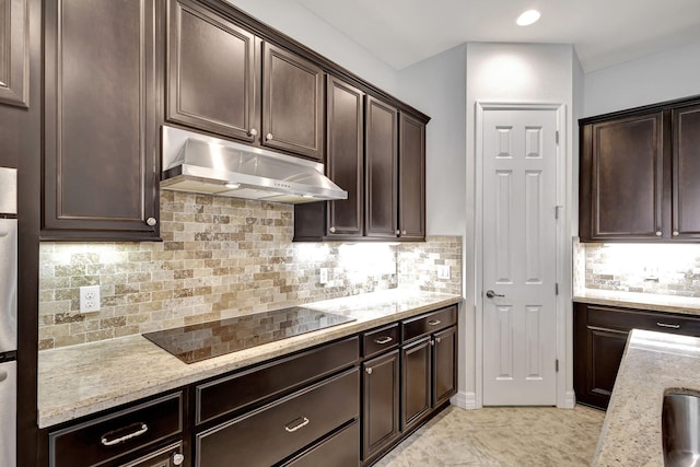 kitchen featuring black electric cooktop, backsplash, dark brown cabinetry, and light stone countertops