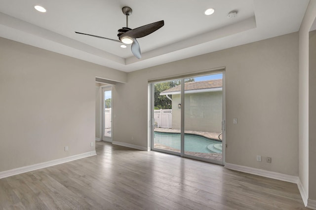 spare room featuring light hardwood / wood-style floors, a raised ceiling, and ceiling fan