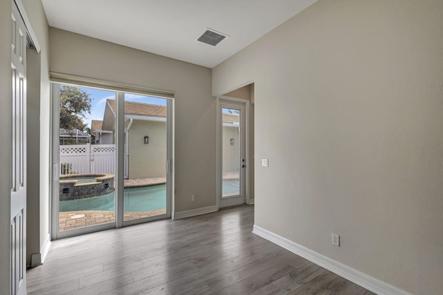 unfurnished room featuring baseboards, visible vents, and wood finished floors