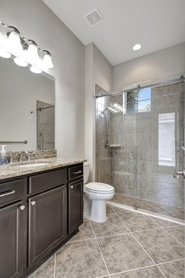 full bathroom featuring toilet, vanity, visible vents, a shower stall, and tile patterned floors