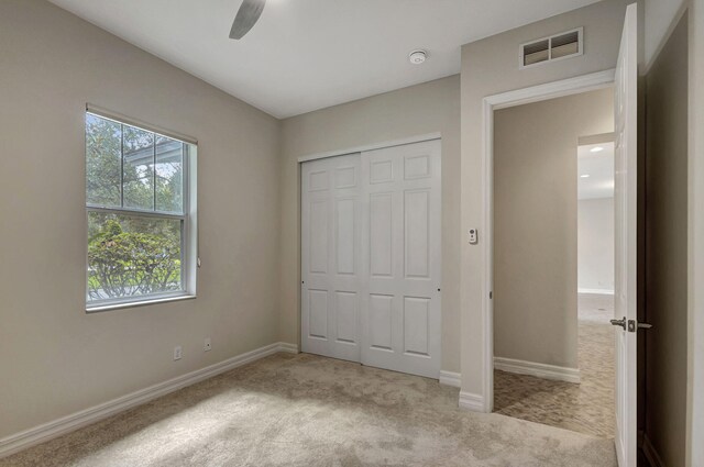 unfurnished bedroom with light carpet, ceiling fan, and a closet