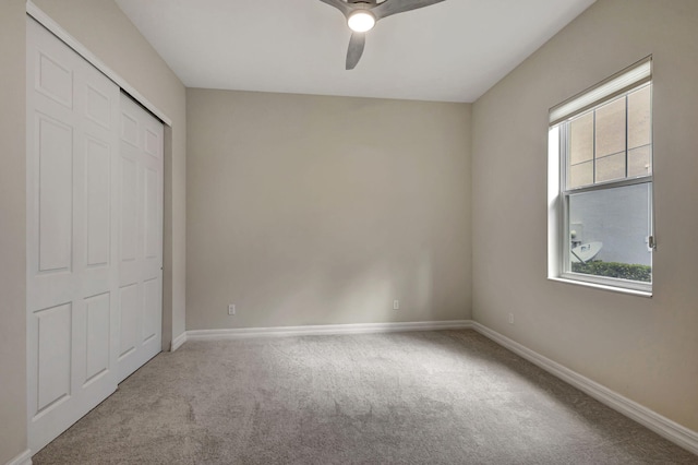 unfurnished bedroom with a closet, carpet flooring, a ceiling fan, and baseboards