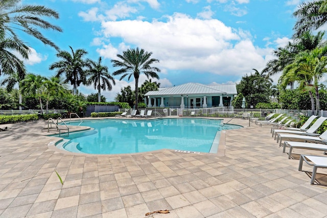 community pool with a patio area and fence