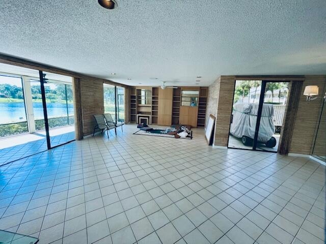 unfurnished living room featuring a large fireplace, a textured ceiling, and light tile patterned floors