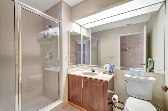 bathroom featuring vanity, toilet, and a shower with shower door