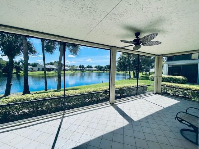 unfurnished sunroom featuring a water view and ceiling fan