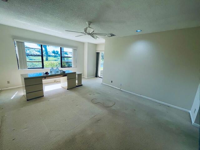 interior space with ceiling fan, light colored carpet, and a textured ceiling