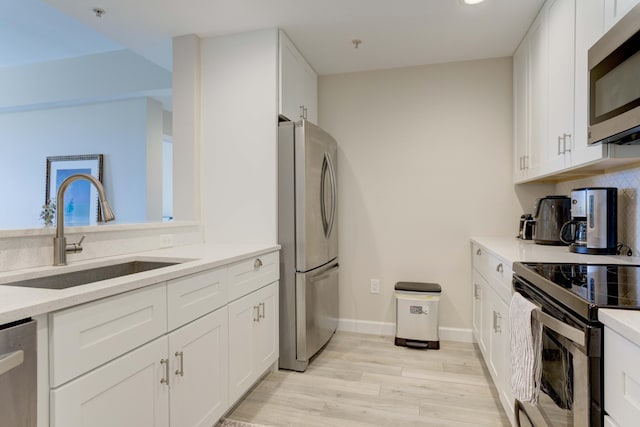 kitchen featuring light hardwood / wood-style flooring, white cabinets, stainless steel appliances, and sink