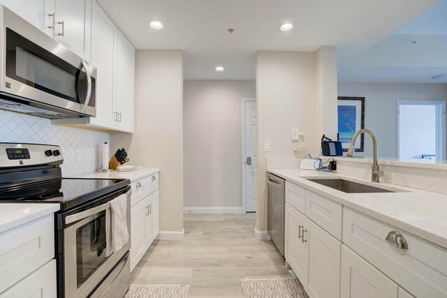 kitchen featuring decorative backsplash, stainless steel appliances, sink, and white cabinetry