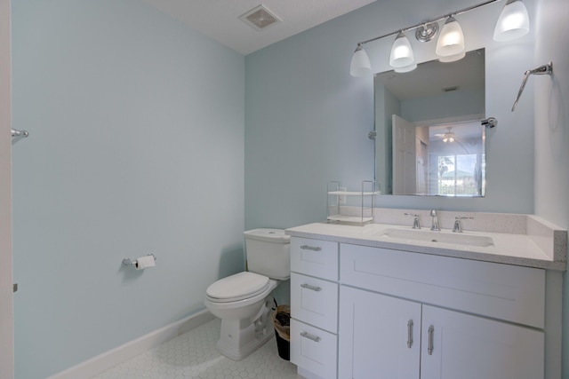 bathroom with toilet, vanity, and tile patterned flooring