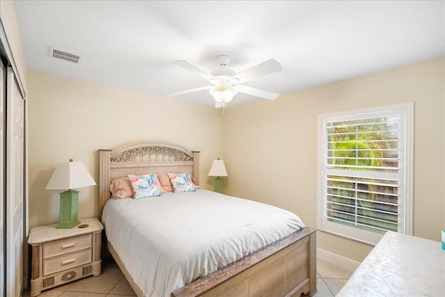 tiled bedroom with ceiling fan and a closet