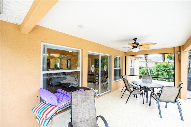 sunroom / solarium featuring beam ceiling and ceiling fan