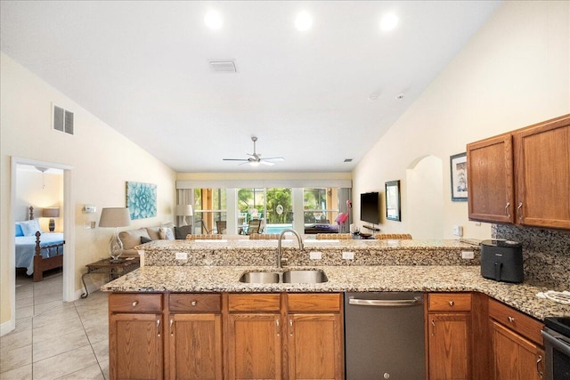 kitchen with ceiling fan, sink, light stone counters, stainless steel dishwasher, and vaulted ceiling