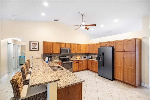 kitchen with sink, a kitchen breakfast bar, high vaulted ceiling, kitchen peninsula, and appliances with stainless steel finishes