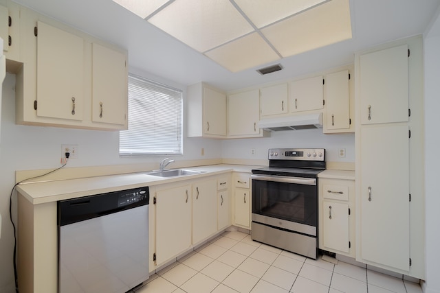 kitchen with appliances with stainless steel finishes, light tile patterned floors, sink, and cream cabinetry