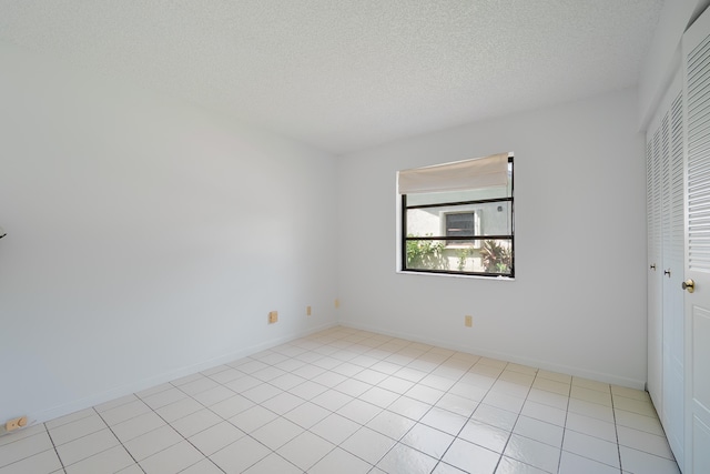 unfurnished room featuring a textured ceiling and light tile patterned floors