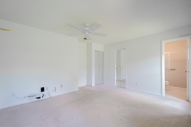 unfurnished bedroom with ensuite bath, a textured ceiling, ceiling fan, and carpet floors