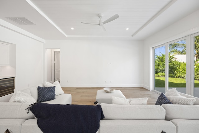 living room featuring a raised ceiling, ceiling fan, and hardwood / wood-style flooring