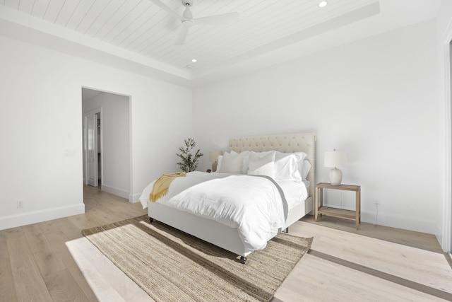 bedroom featuring wood ceiling, light hardwood / wood-style flooring, ceiling fan, and a raised ceiling