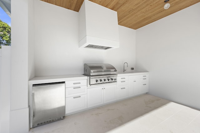 kitchen with white cabinets, stainless steel fridge, sink, and wooden ceiling