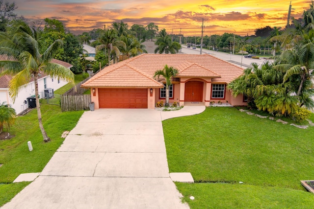 mediterranean / spanish-style home with a lawn and a garage