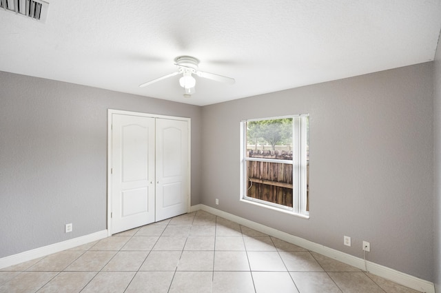 unfurnished bedroom featuring ceiling fan, a closet, and light tile patterned flooring