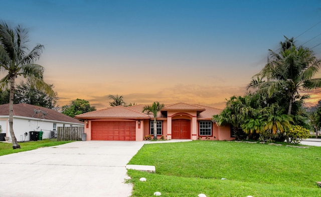 mediterranean / spanish-style home with a garage and a lawn