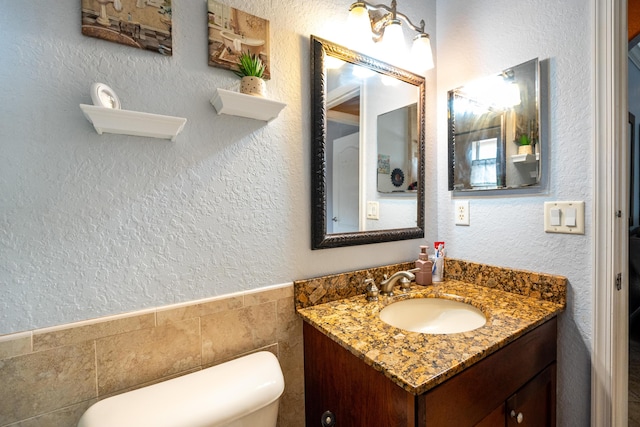 bathroom featuring toilet, tile walls, and vanity