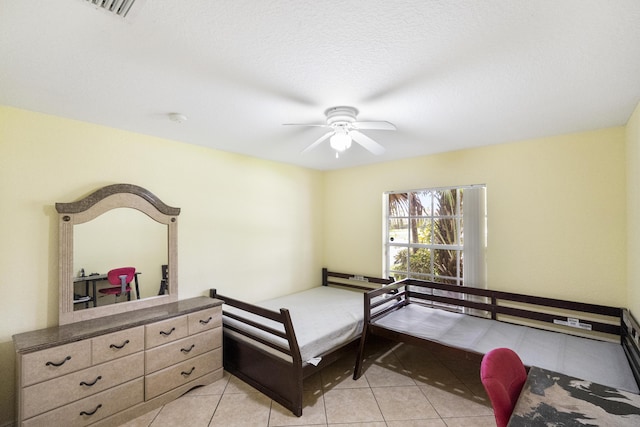 bedroom with ceiling fan, light tile patterned floors, and a textured ceiling