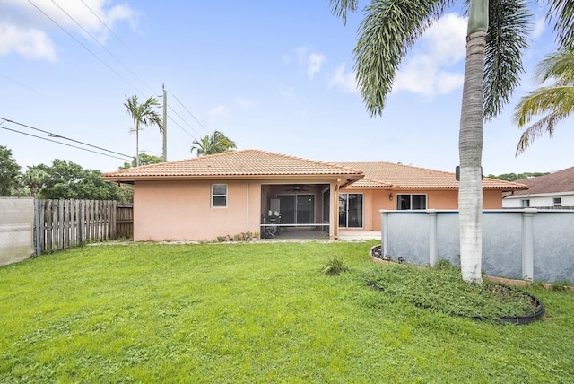 back of property featuring a lawn, ceiling fan, a fenced in pool, and a sunroom