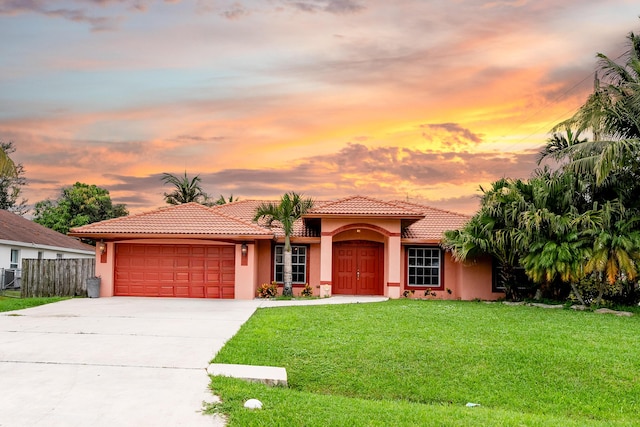 mediterranean / spanish-style home with a garage and a lawn