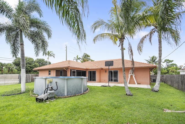 rear view of property featuring a fenced in pool and a lawn