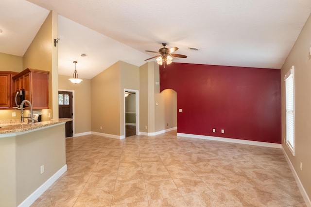 interior space featuring a ceiling fan, arched walkways, plenty of natural light, and baseboards