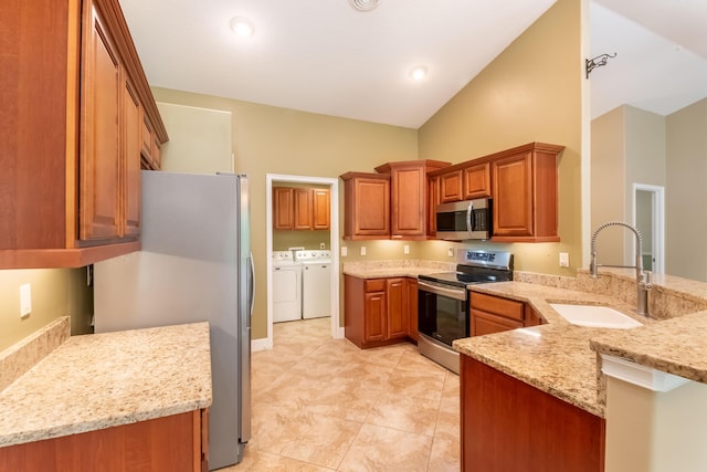 kitchen with brown cabinetry, light stone counters, independent washer and dryer, stainless steel appliances, and a sink