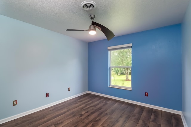 spare room with dark wood finished floors, visible vents, a ceiling fan, a textured ceiling, and baseboards