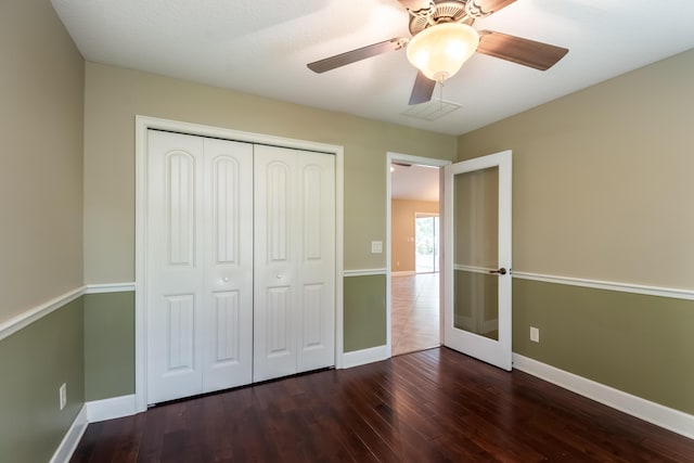 unfurnished bedroom featuring dark wood-style floors, a closet, and baseboards