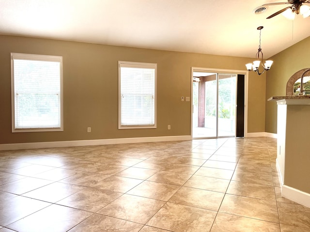 spare room featuring light tile patterned floors, baseboards, visible vents, lofted ceiling, and ceiling fan with notable chandelier