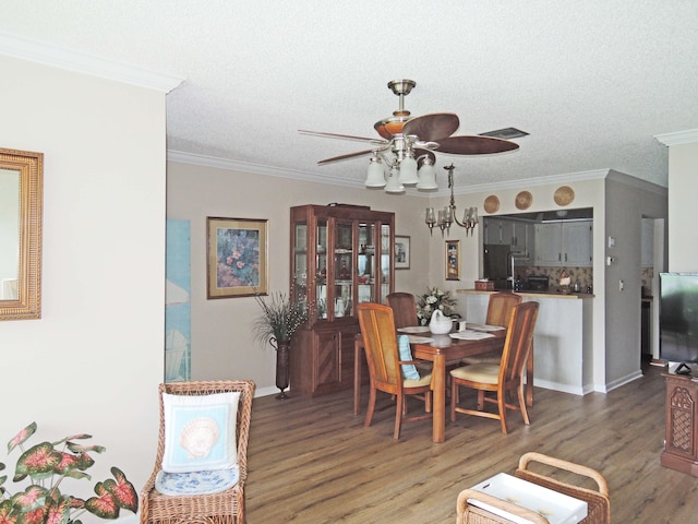 dining area with dark wood-type flooring, a textured ceiling, ceiling fan, and crown molding