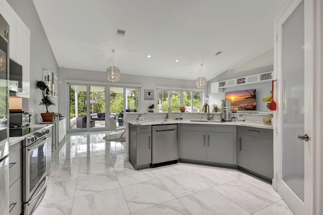 kitchen with appliances with stainless steel finishes, gray cabinetry, vaulted ceiling, and decorative light fixtures