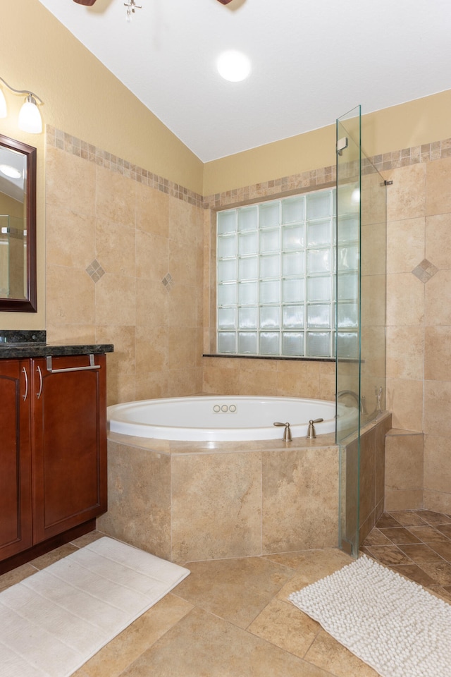 bathroom with shower with separate bathtub, tile walls, vanity, and tile patterned flooring