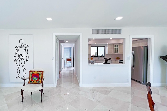 interior space with baseboards, visible vents, freestanding refrigerator, marble finish floor, and a sink